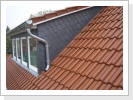 Eine Schleppgaube mit Schiefer bekleidet in einem Tonziegel Dach in Hattenheim